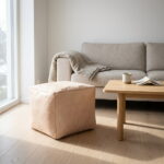 Undyed leather cube ottoman in a bright Scandinavian living room beside an oak coffee table