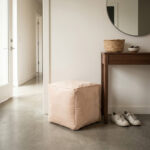 Undyed square leather ottoman in a modern entryway next to a walnut console table